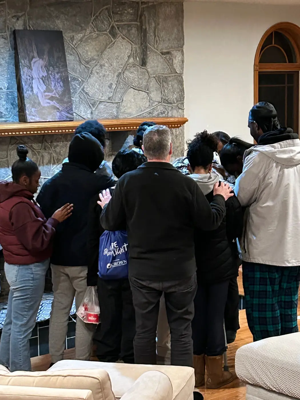 A group praying together beside a fireplace at Haven House