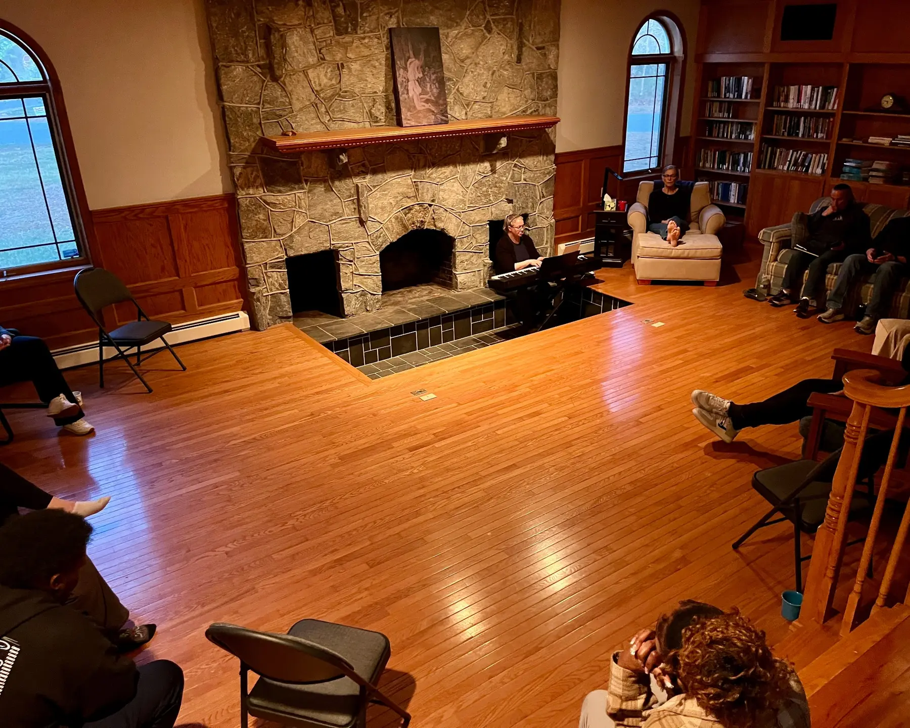 A worship gathering around a piano in the Haven House great room