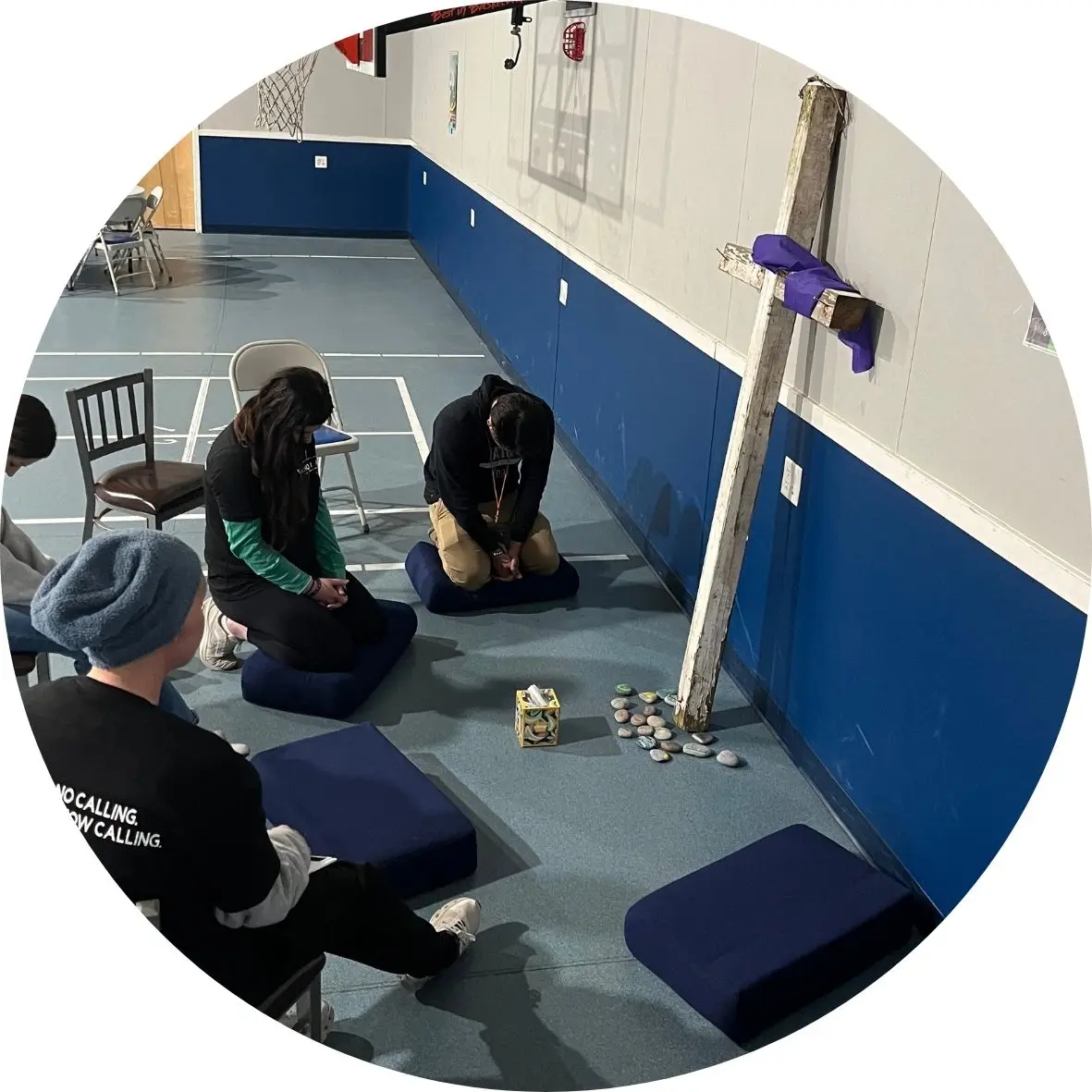 Participants praying quietly near a wooden cross